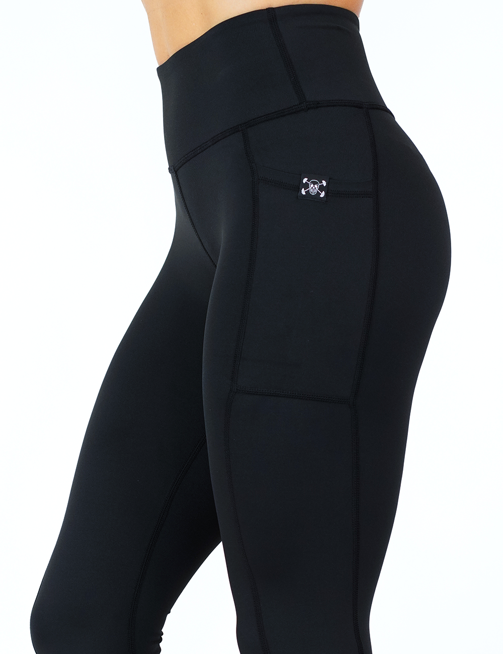 close up of solid black leggings with mini skull and barbells logo on side pocket