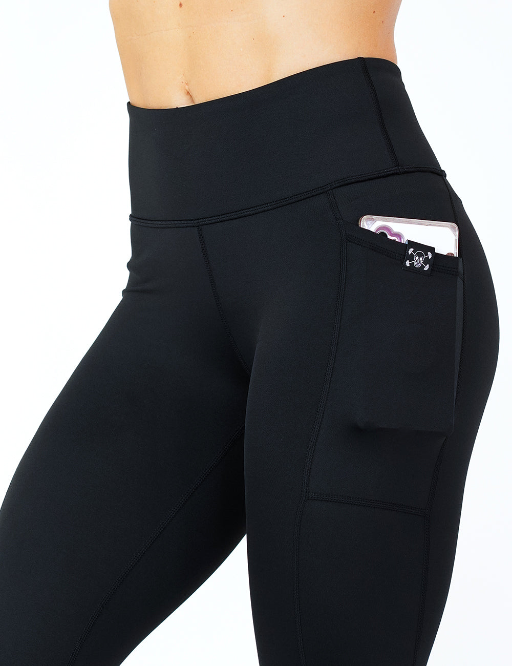 close up of the solid black leggings holding a phone in its pocket