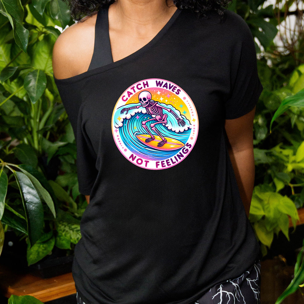 shirt with a skeleton surfing graphic on it that says "Catch Waves Not Feelings"