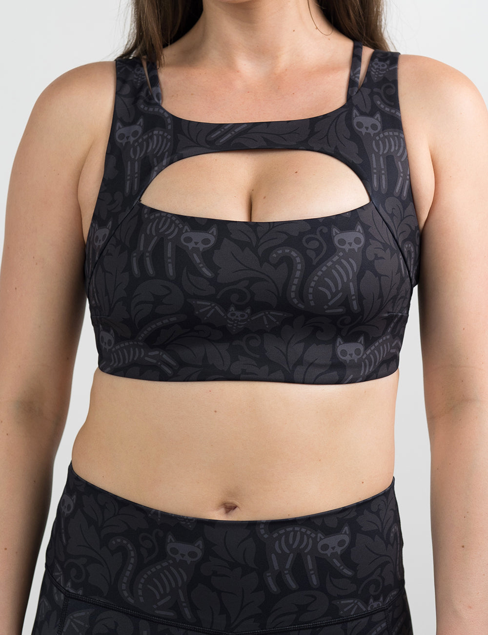 front of the black and grey bats and cats skeleton sports bra against a white background