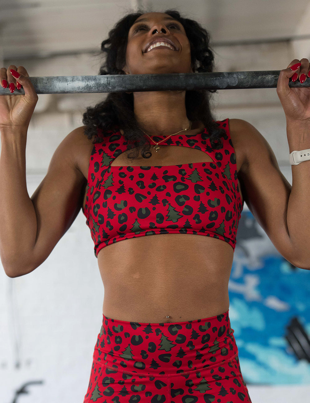 model wearing the red and brown Christmas trees and leopard print sports bra doing pull ups