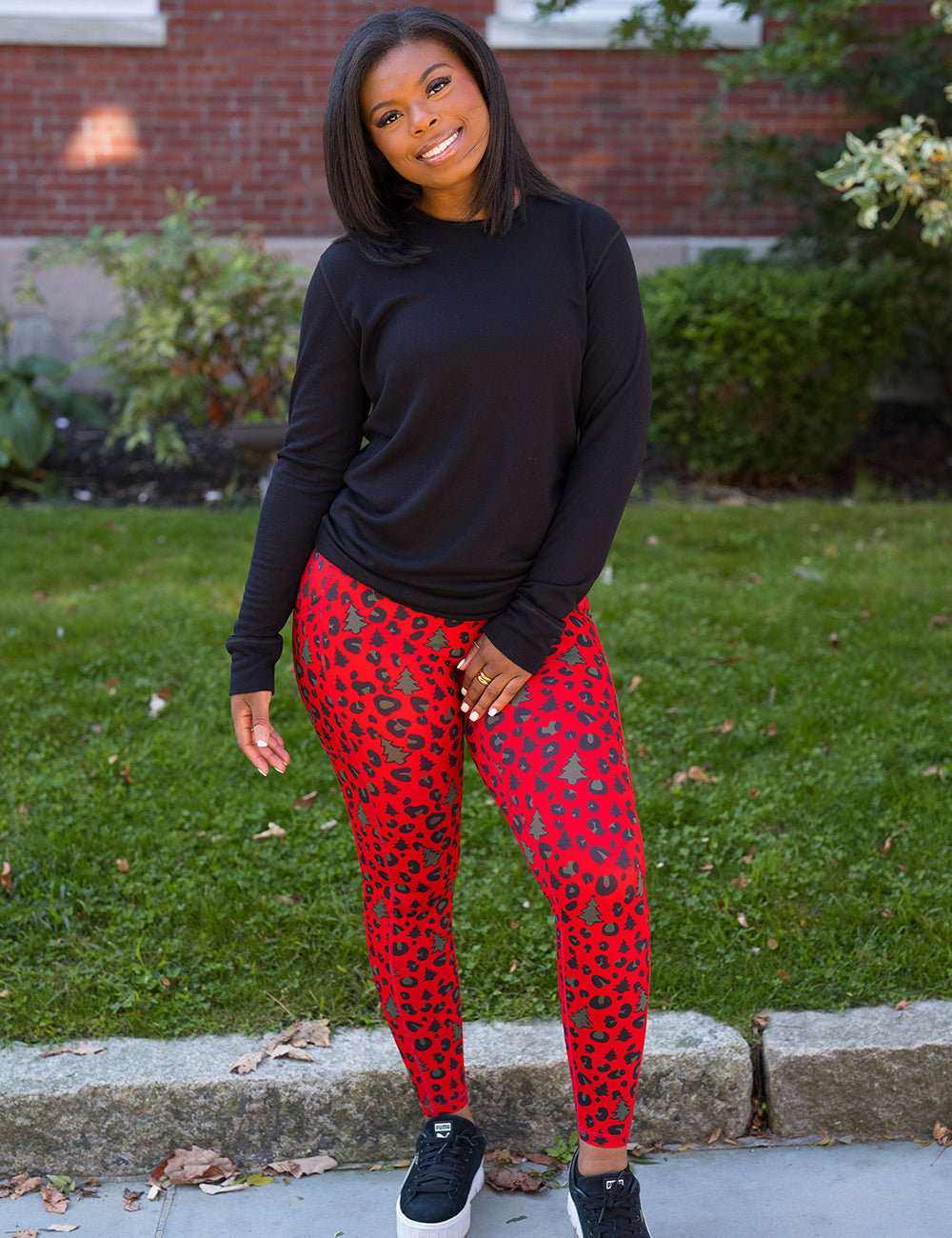 model wearing the red and brown Christmas trees and leopard print full length leggings and a black long sleeve