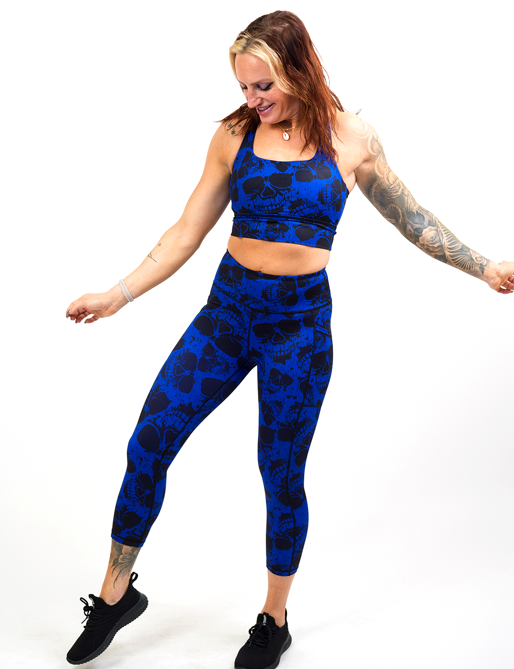 model wearing the dark skulls against a blue background pattern capri leggings against a white background