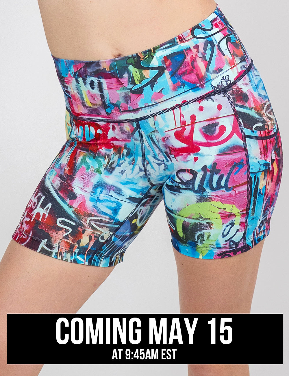 front of the 5 inch multi colored graffiti pattern shorts against a white background, coming may 15th