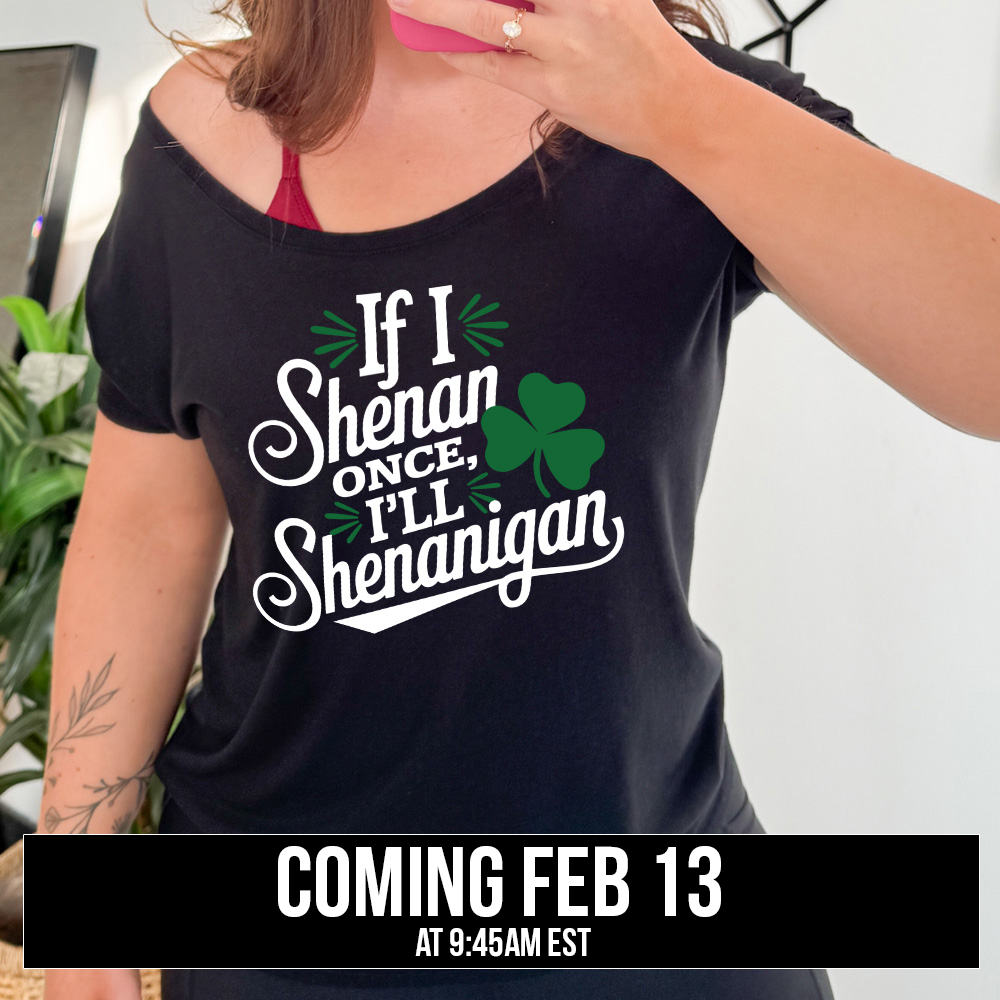 black slouchy tee with the words "if I shenan once, I'll shenanigan" on it, with the graphic of a shamrock, coming soon