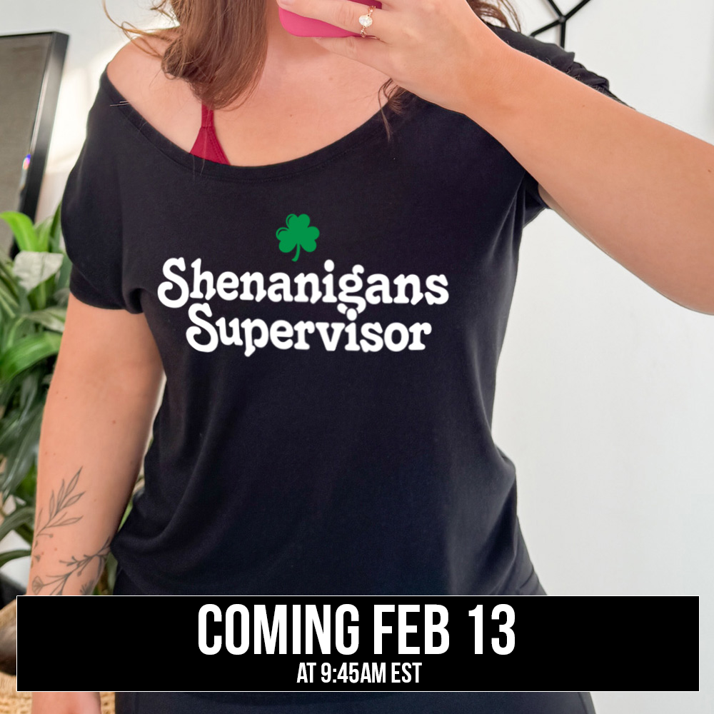 black slouchy tee with the words "shenanigans supervisor" on it, with one small clover graphic above it, coming soon