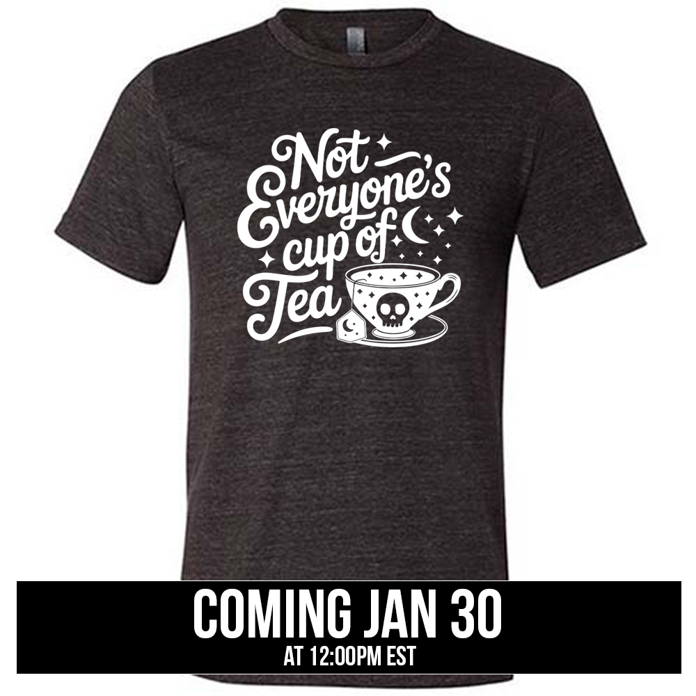 black unisex tee with the words "not everyone's cup of a tea" in a cursive font, with the graphics of a moon and little stars, and a tea cup with a skull on it with stars and the tea bag has a moon on it, coming soon
