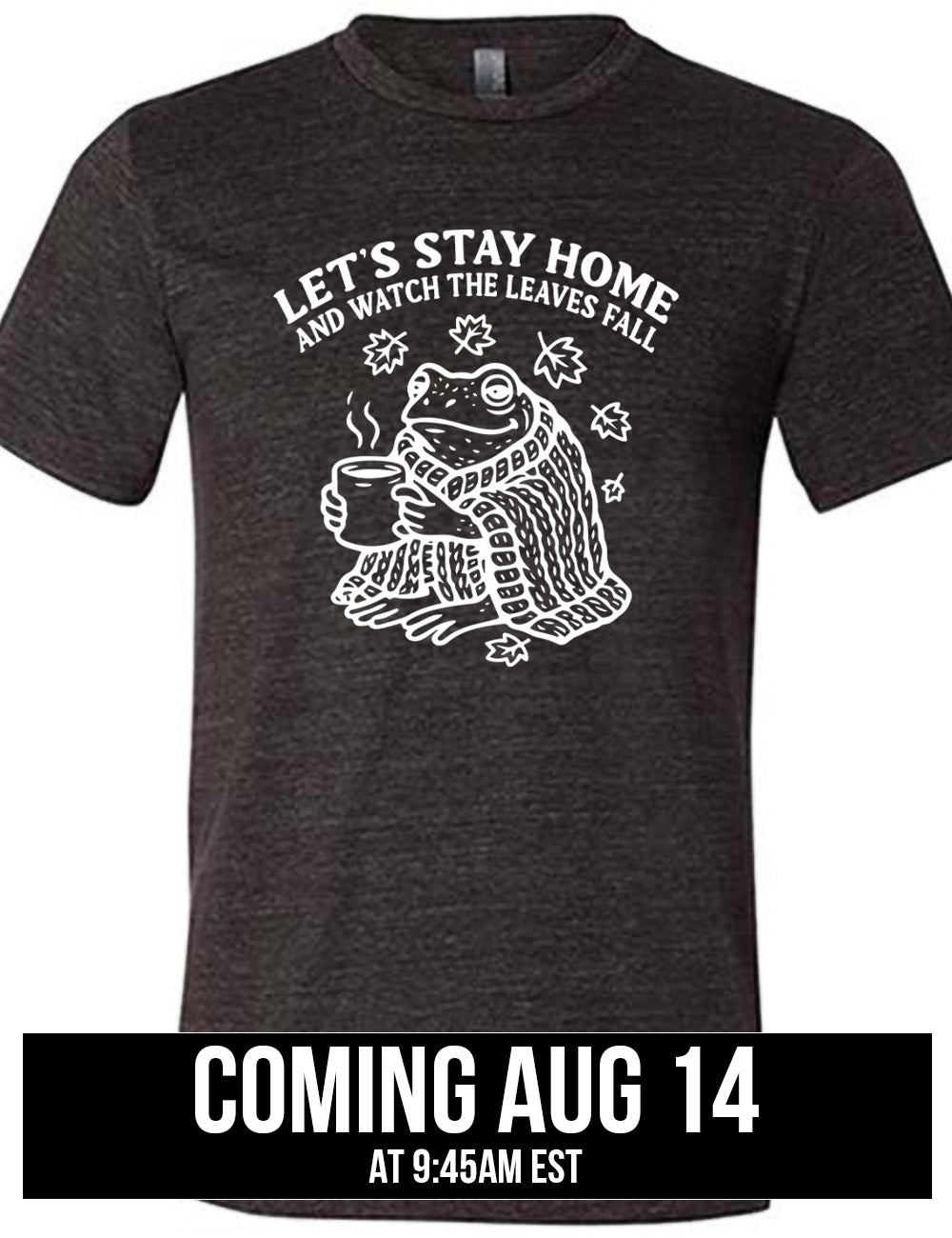 black unisex tee with the words "let's stay home and watch the leaves fall" on it, and the graphic underneath of a frog, wrapped in a blanket, holding a mug of steaming beverage, with five leaves arching over it coming august 14th