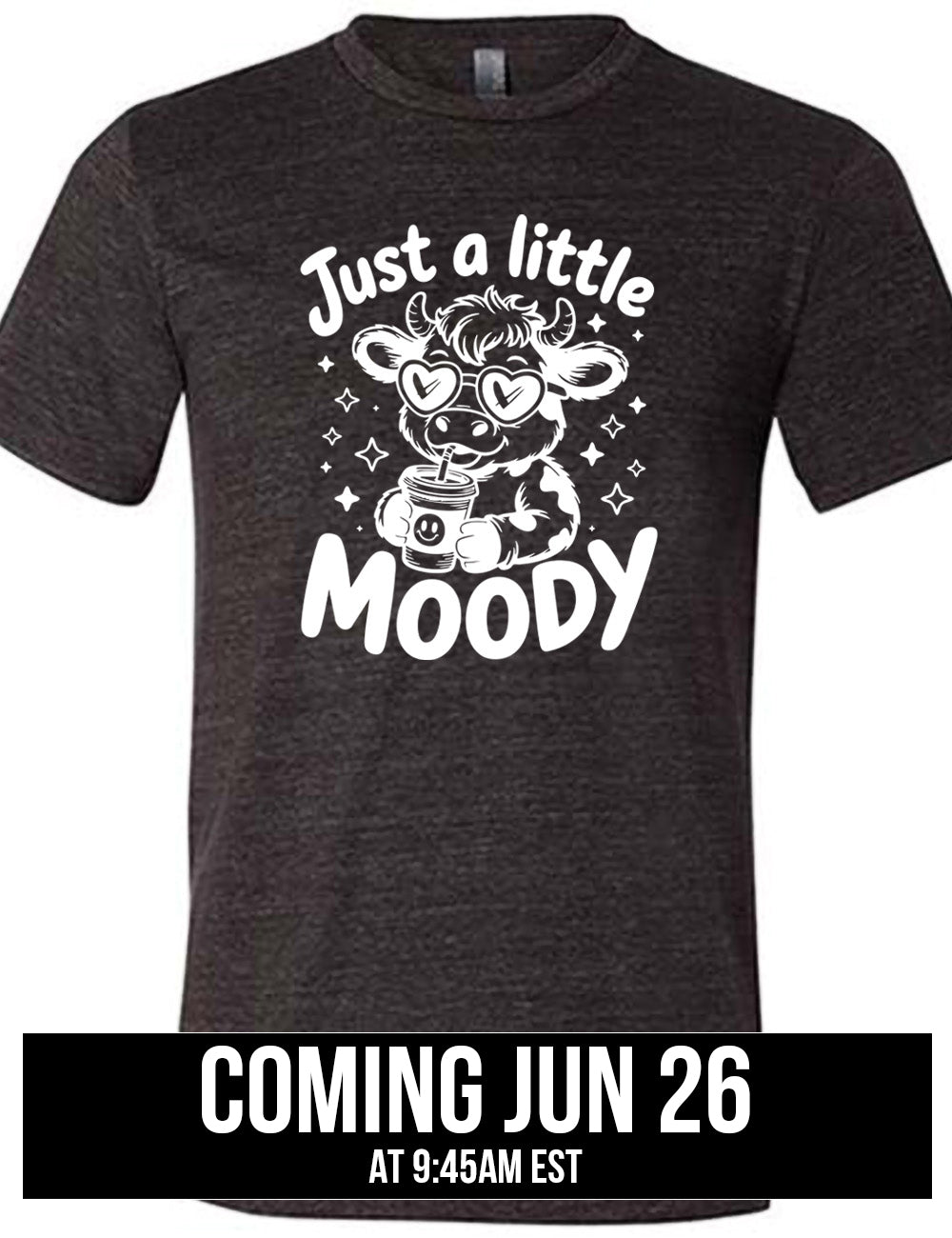 black unisex tee with the graphic of a cartoon cow, wearing heart sunglasses and drinking out of an iced cup with a straw, surrounded by little stars, as well as the words "just a little moody" around it, coming june 26th