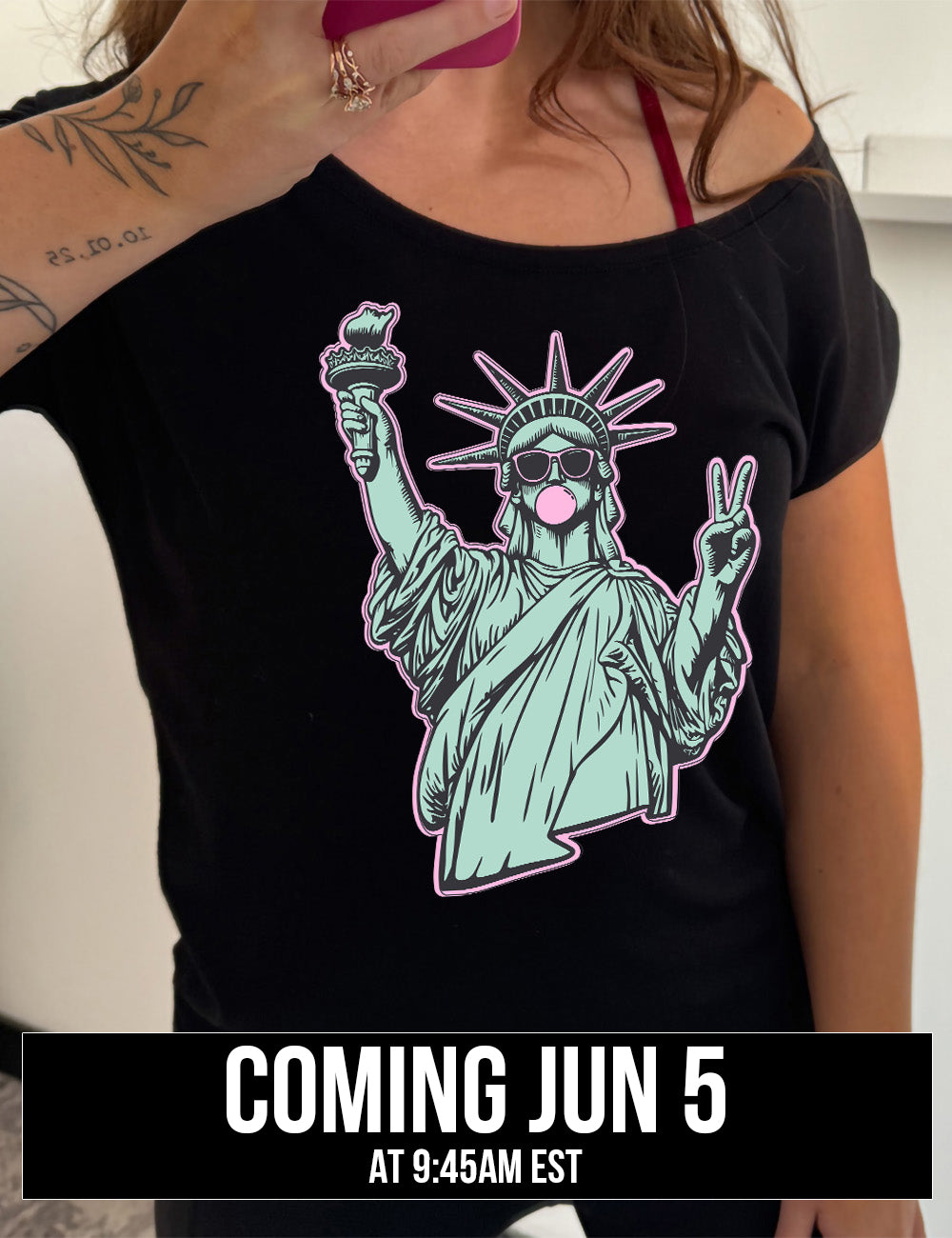 black slouchy tee with the graphic of the statue of liberty, wearing sunglasses, blowing a gum bubble, and giving the peace sign, coming june 5th
