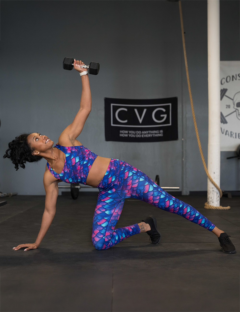 model wearing the blue, purple, and red colored dragon scale leggings and bra while working out in the gym