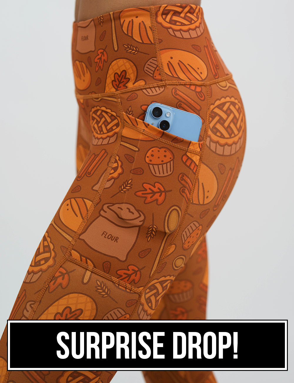 close up of the orange baking themed leggings with a phone in its pocket, surprise drop