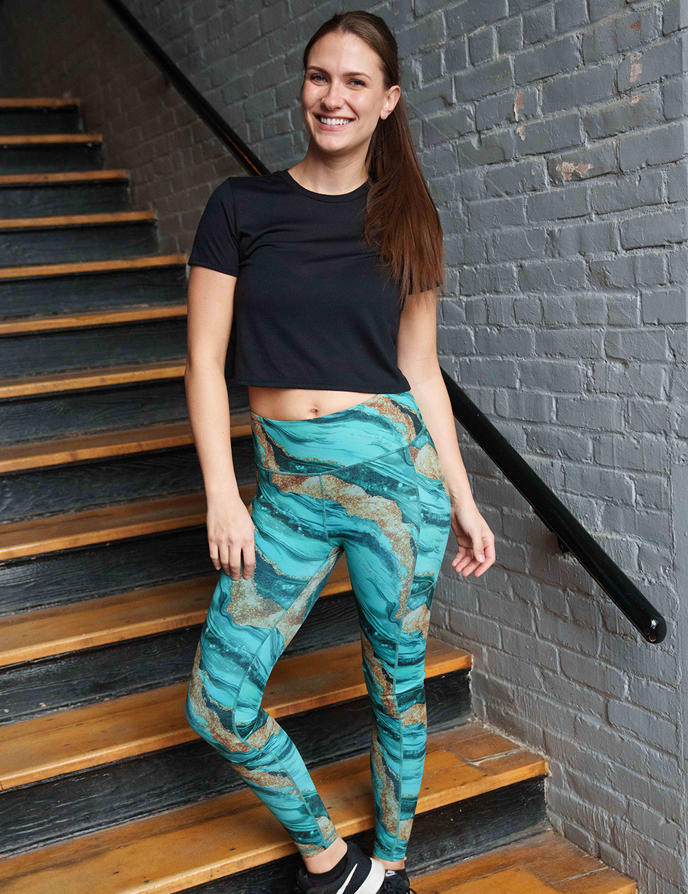 model wearing the full length crystal tides leggings with a black shirt on a stair case