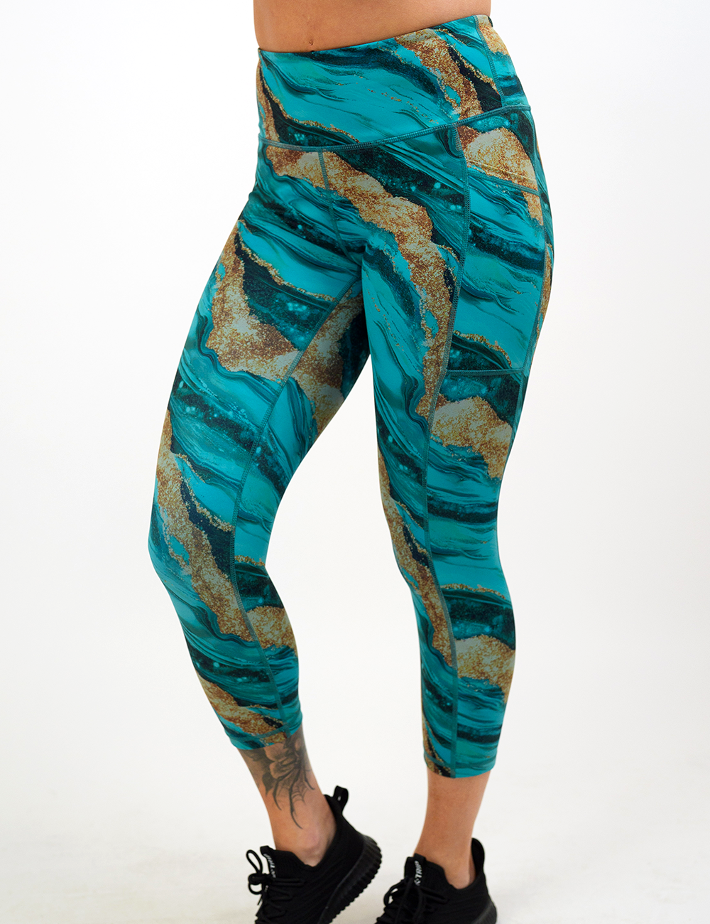 blue ocean with gold streaks patterned capri leggings facing the front against a white background