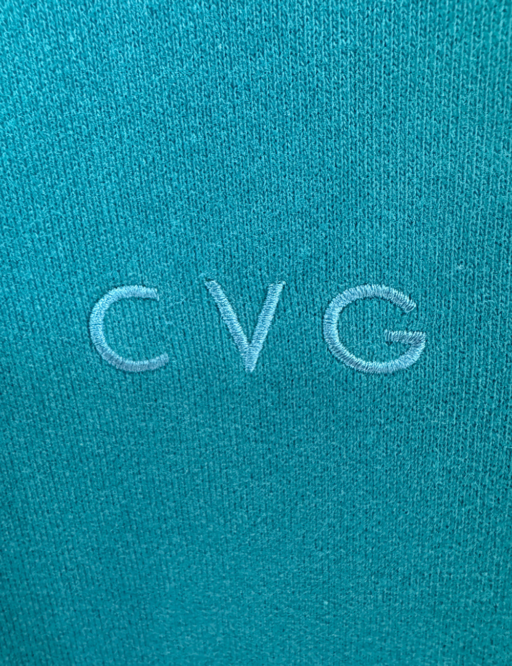 close up of the subtle CVG logo found on the teal unwind hoodies and sweatpants