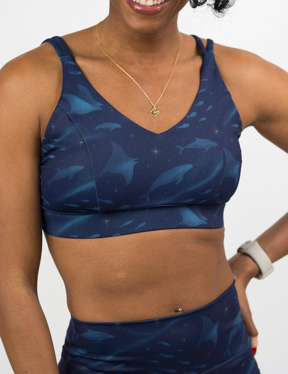 front of the dark blue ocean filled with sting rays, whales, and fish vitality bra against a white background