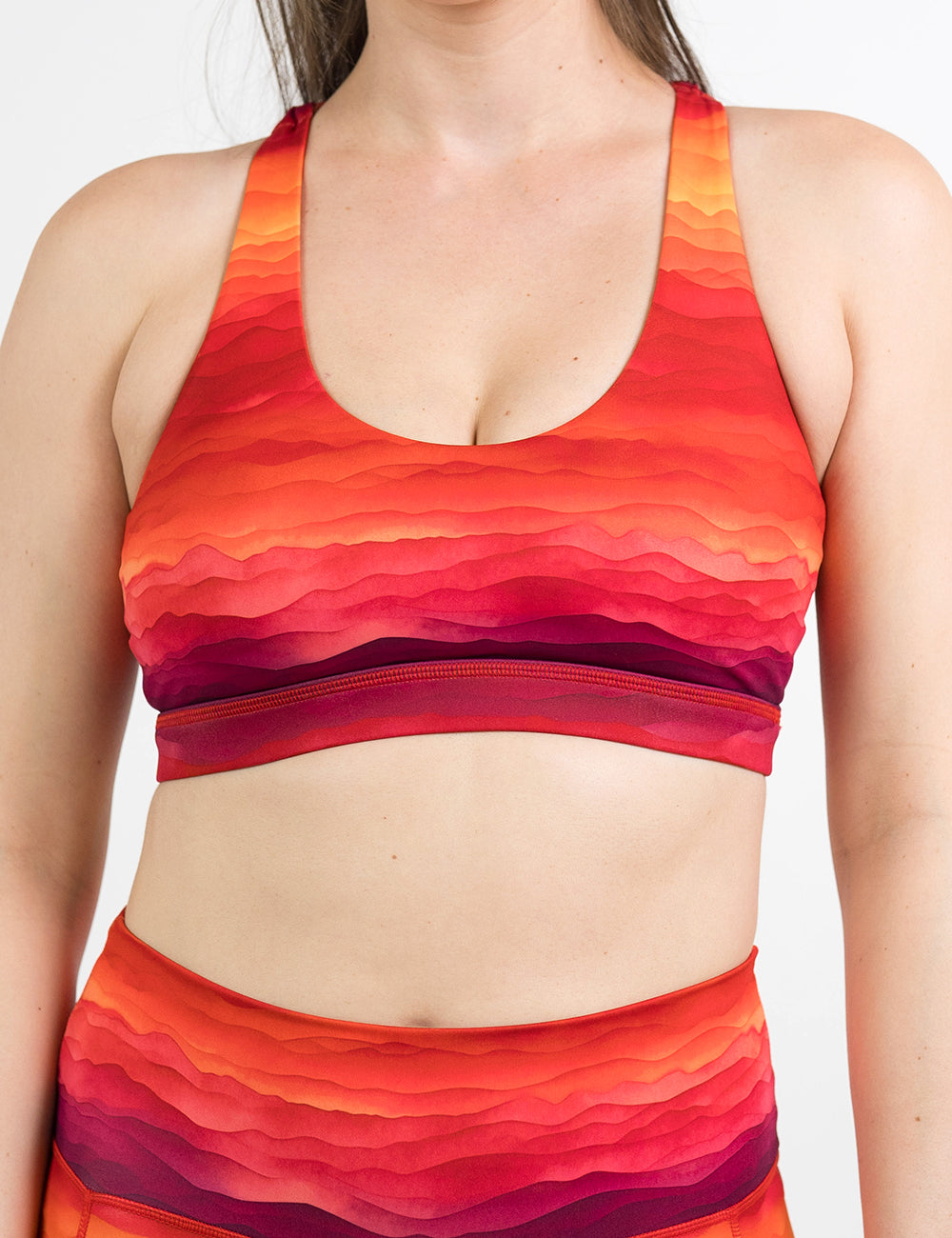 model wearing the red, yellow, and orange sunset stripes pattern butterfly back bra against a white background
