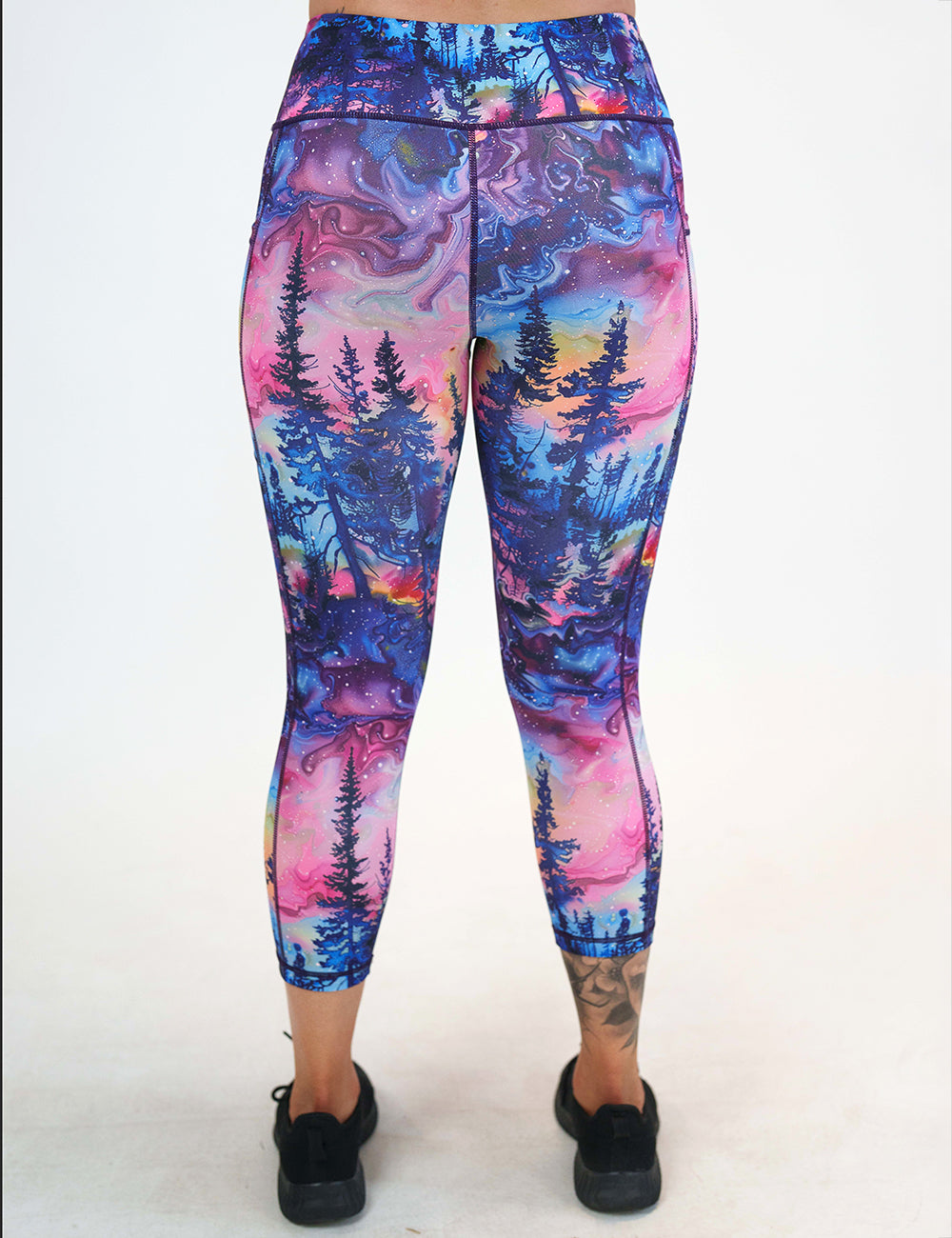 back of the watercolor rainbow patterned forest capri leggings against a white background