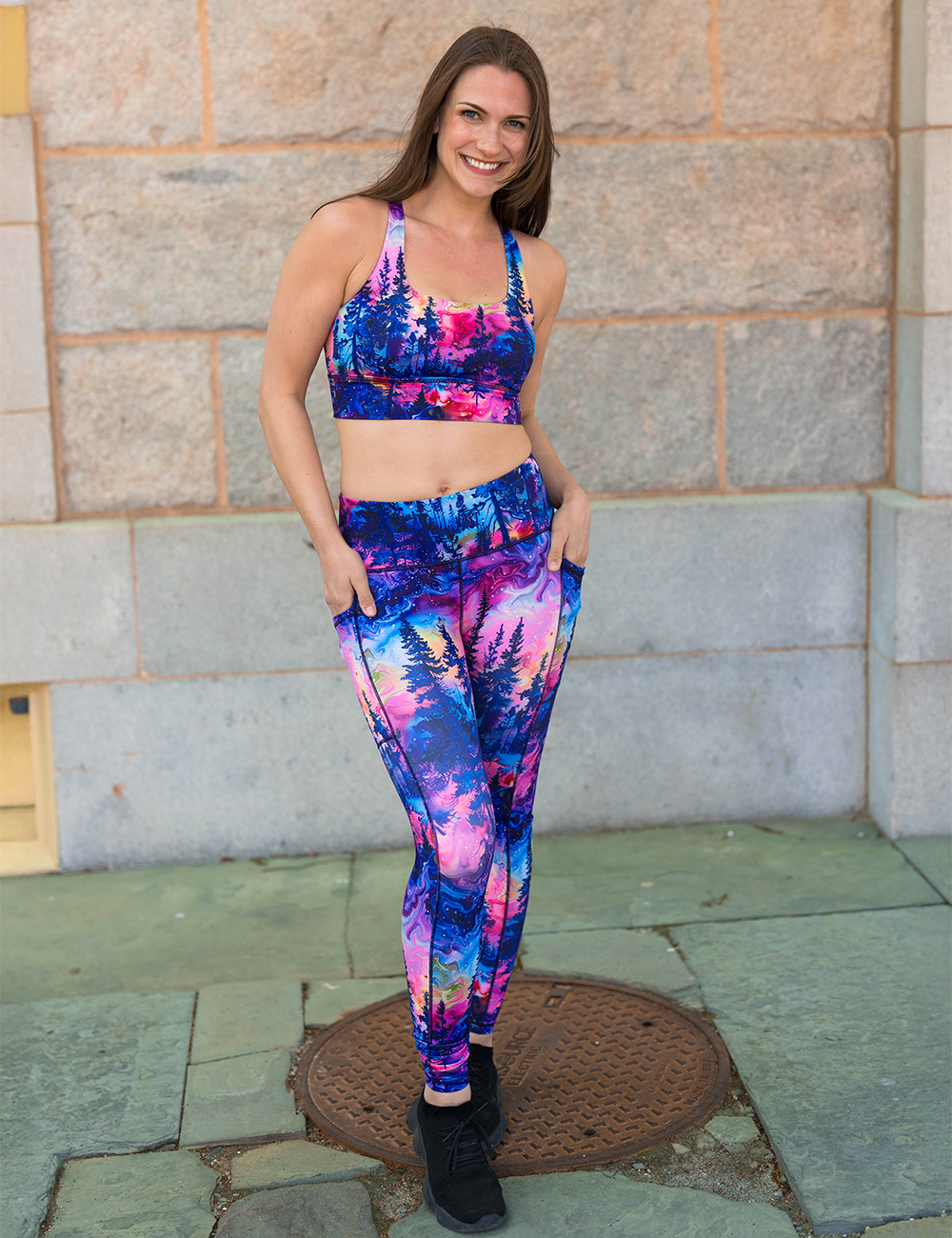 watercolor rainbow patterned forest full length leggings on the sidewalk against a brick building background