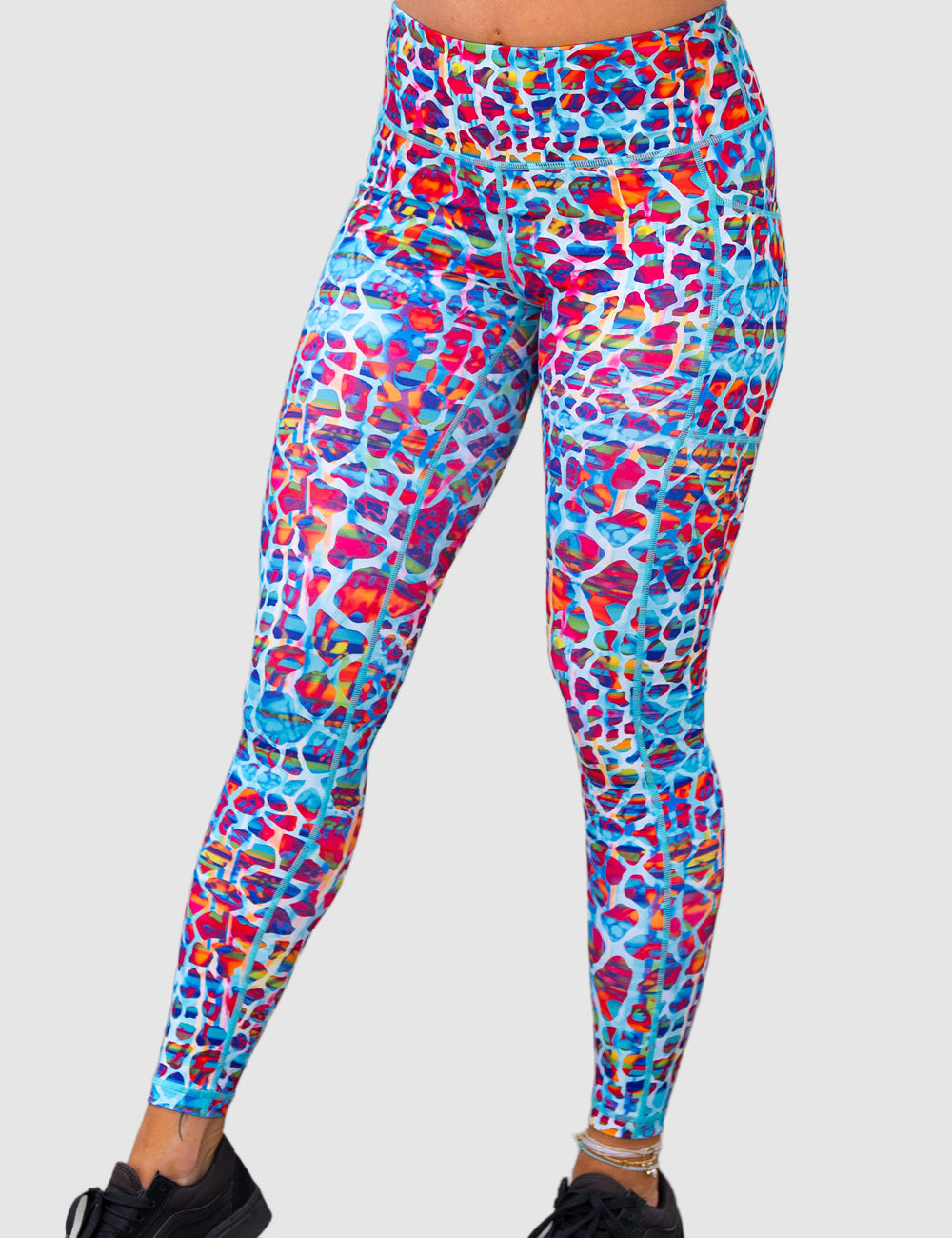 front of the full length turquoise, coral, pink, orange, purple, and yellow mosaic style pattern leggings