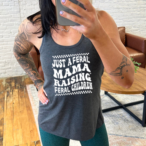 model wearing a grey racerback tank with the saying "just a feral mama raising feral children" on it