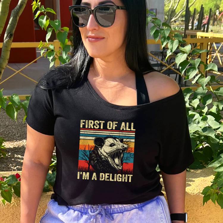 model wearing a black slouchy tee with a possum on it and the saying "first of all I'm a delight"