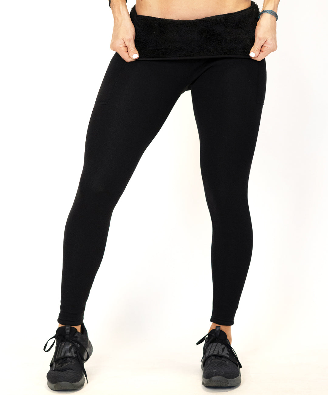 model wearing black fleece leggings folding over the leggings to show the fleece lining inside
