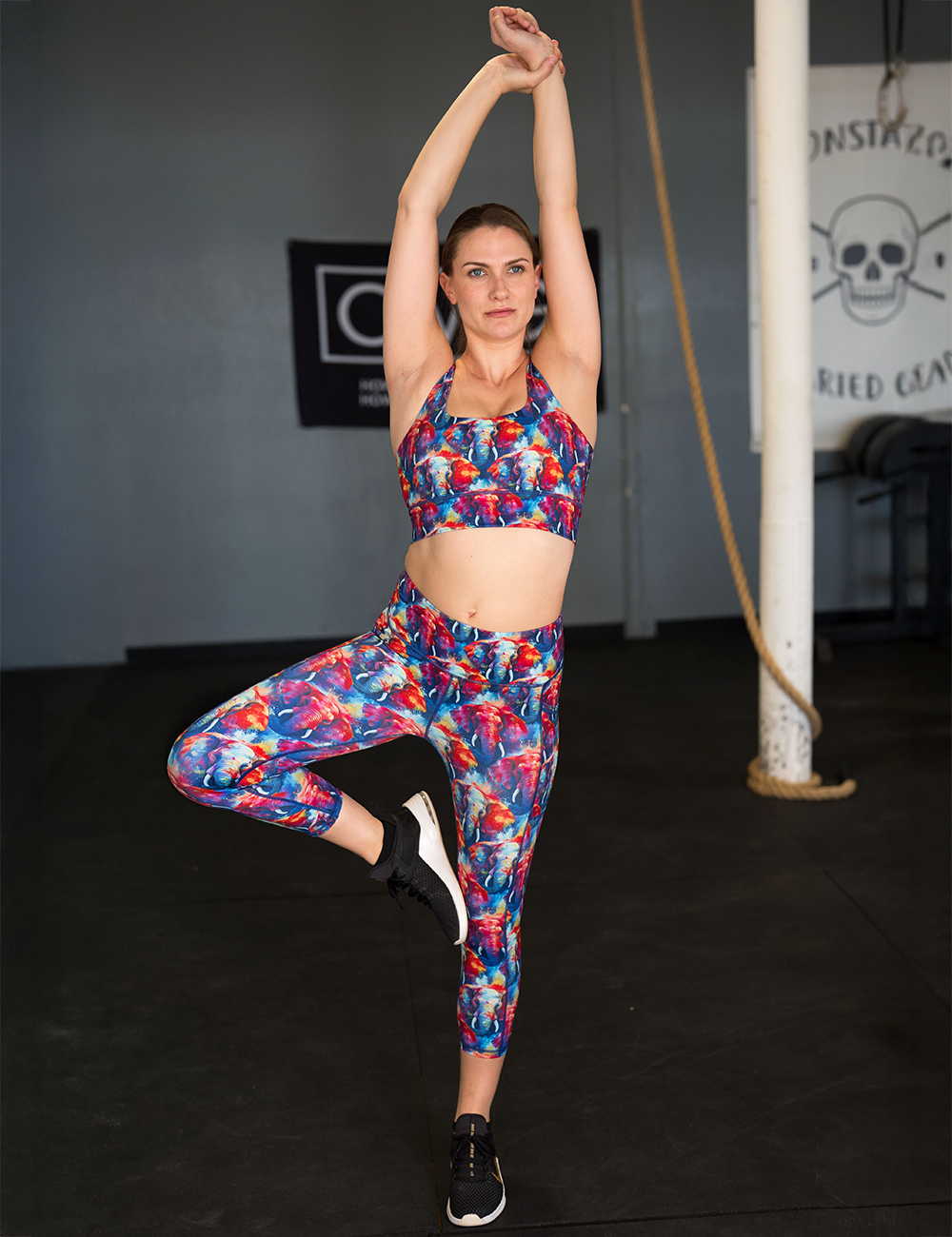 model wearing the colorful elephants leggings and sports bra posing in the gym