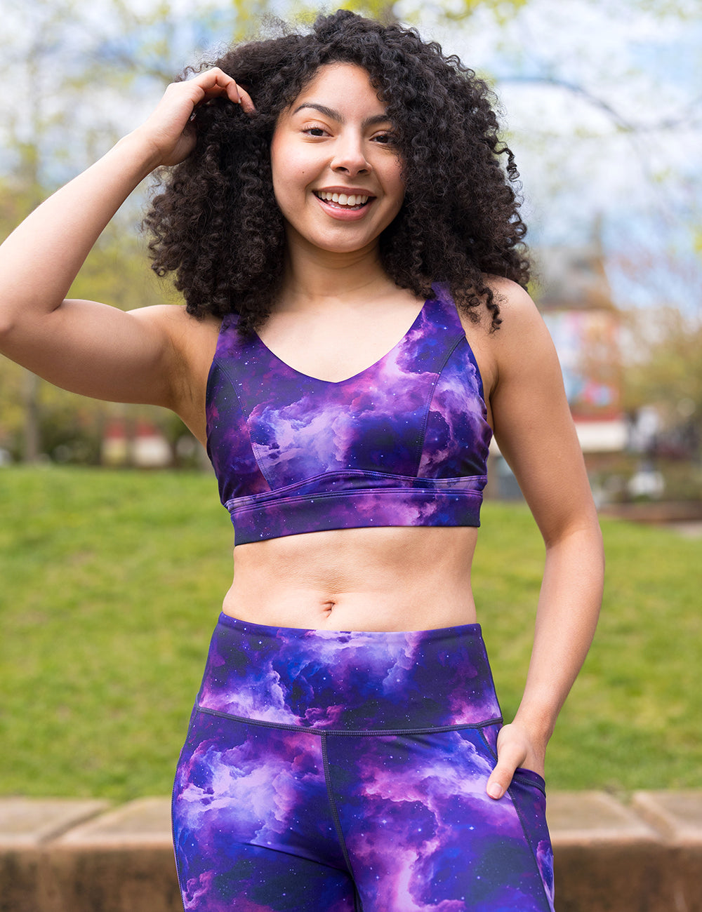 model posing outside in the purple space patterned vitality bra against a white background