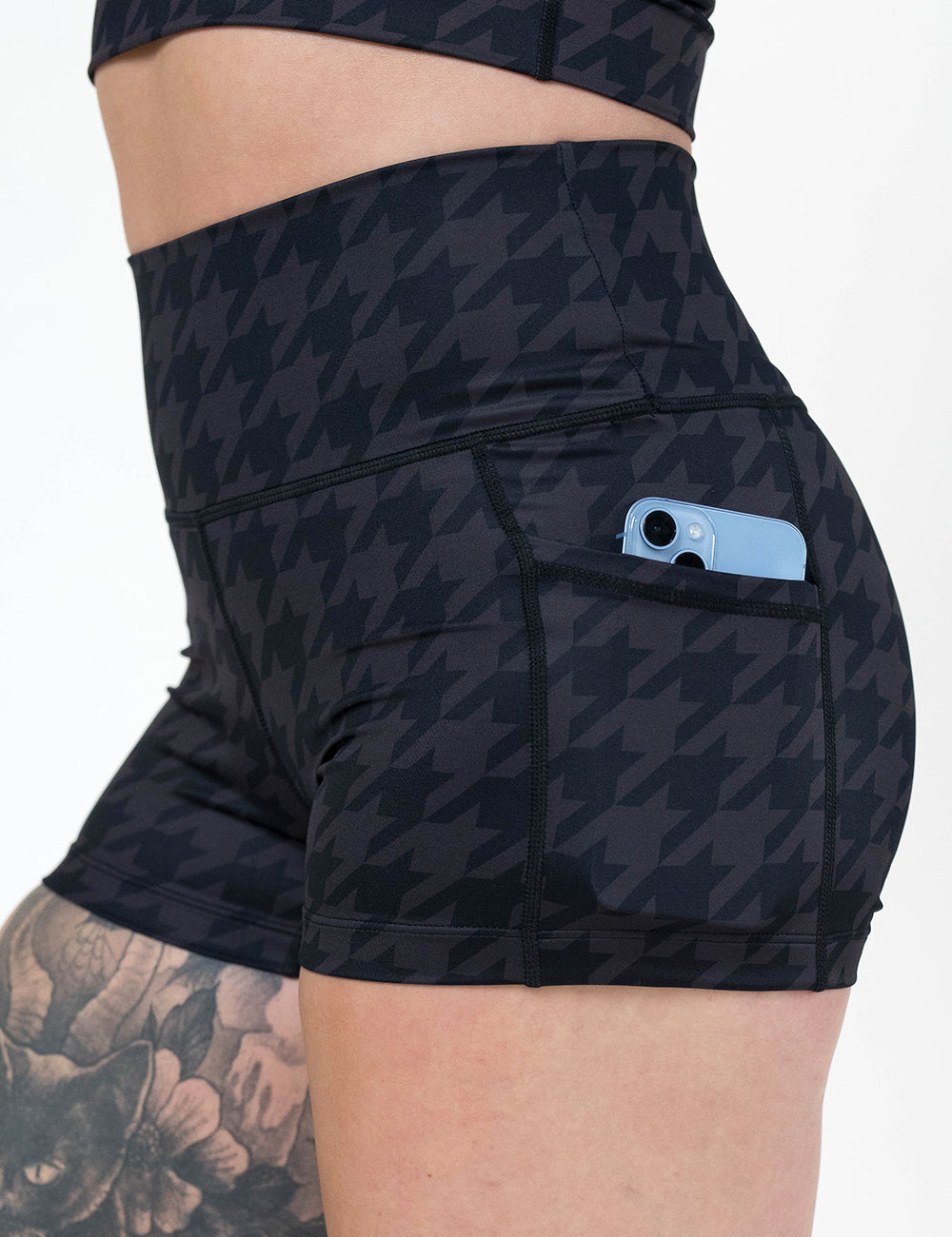 close up of the 2.5 inch dark houndstooth pattern shorts with a phone in its pocket