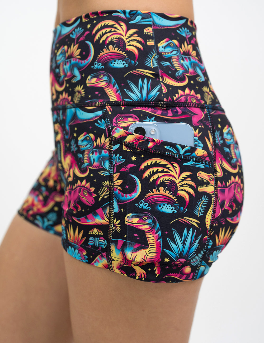 close up of the dinosaur print shorts with a phone in the pocket against a white background