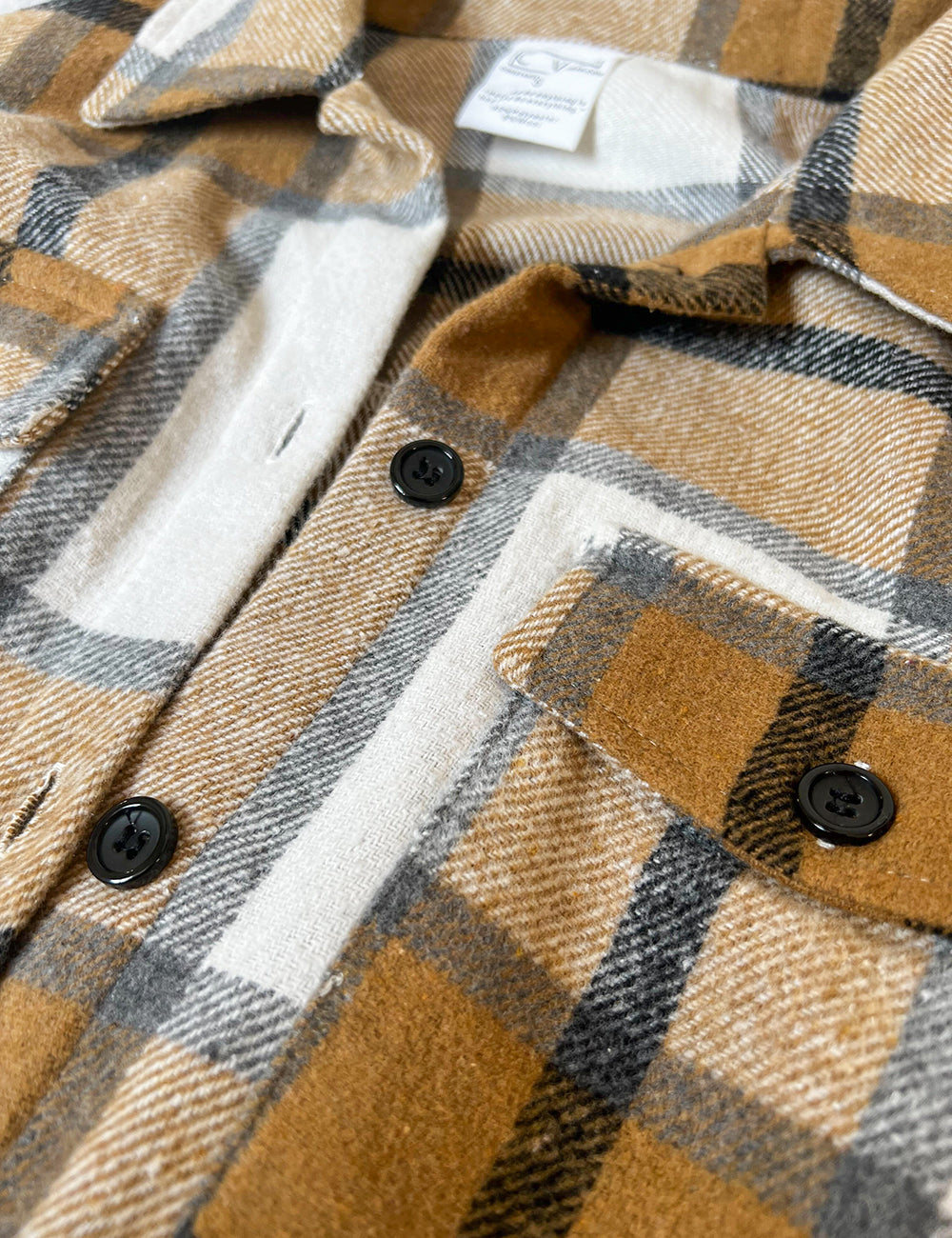 close up of the khaki, black, grey, and white plaid jacket