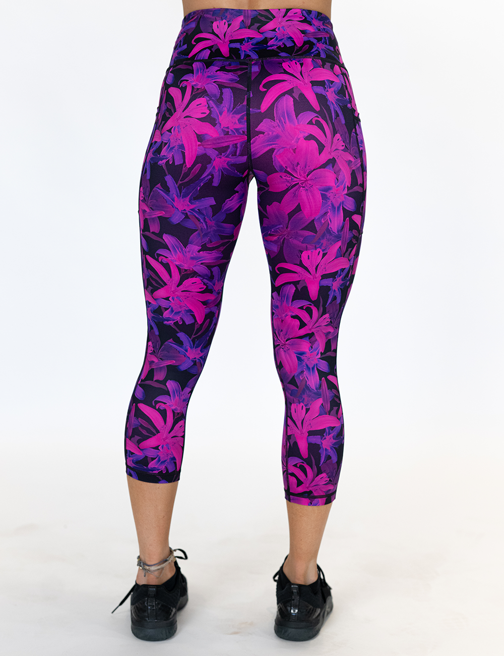 back of the vibrant purple capri leggings against a white background