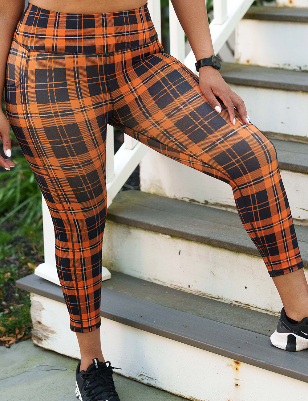 front of the black and orange plaid capri leggings against a white background