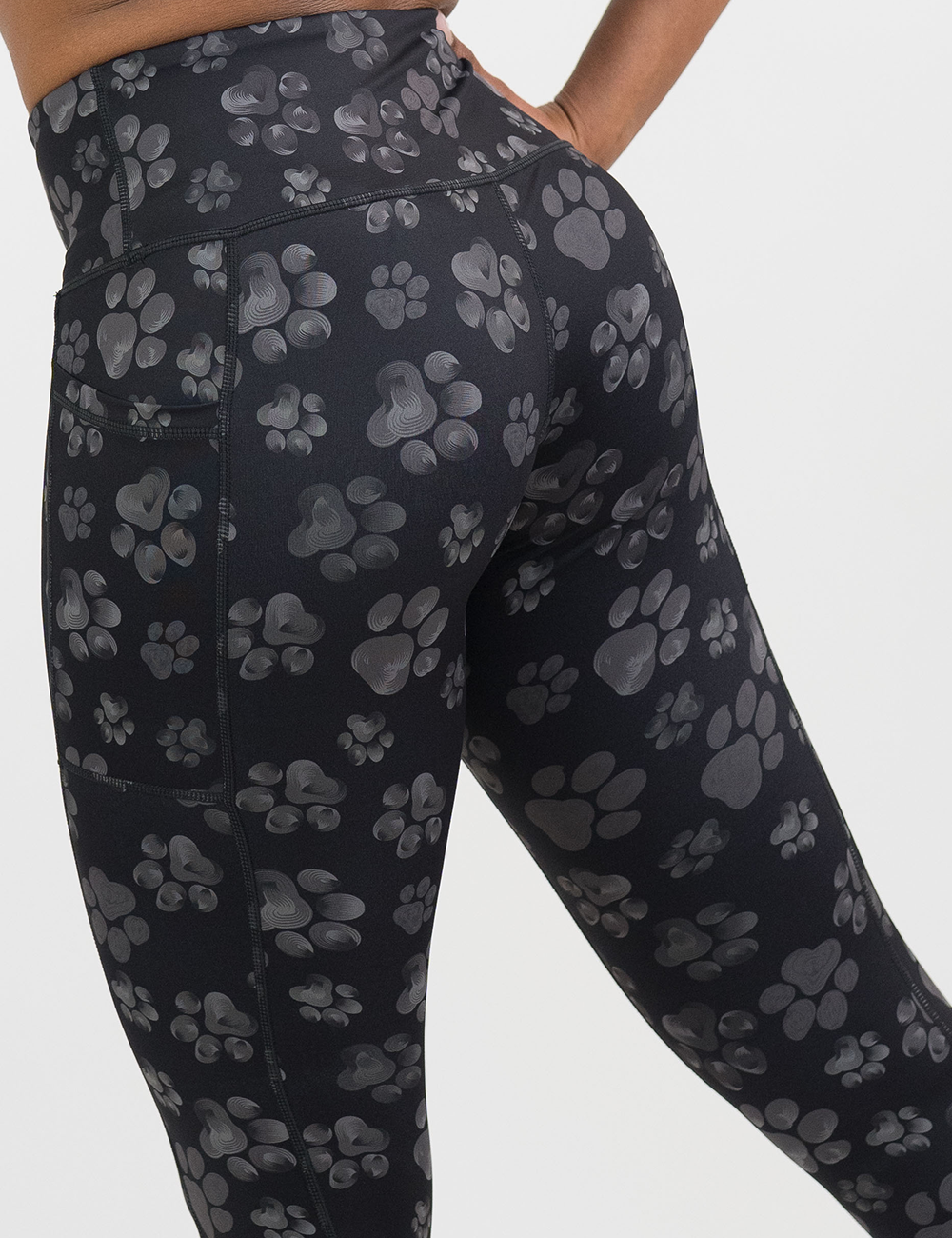 close up of the back of the grey paw prints against a black background leggings