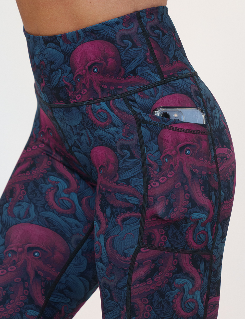 close up of the maroon octopus with glowing blue eyes leggings pocket holding a phone