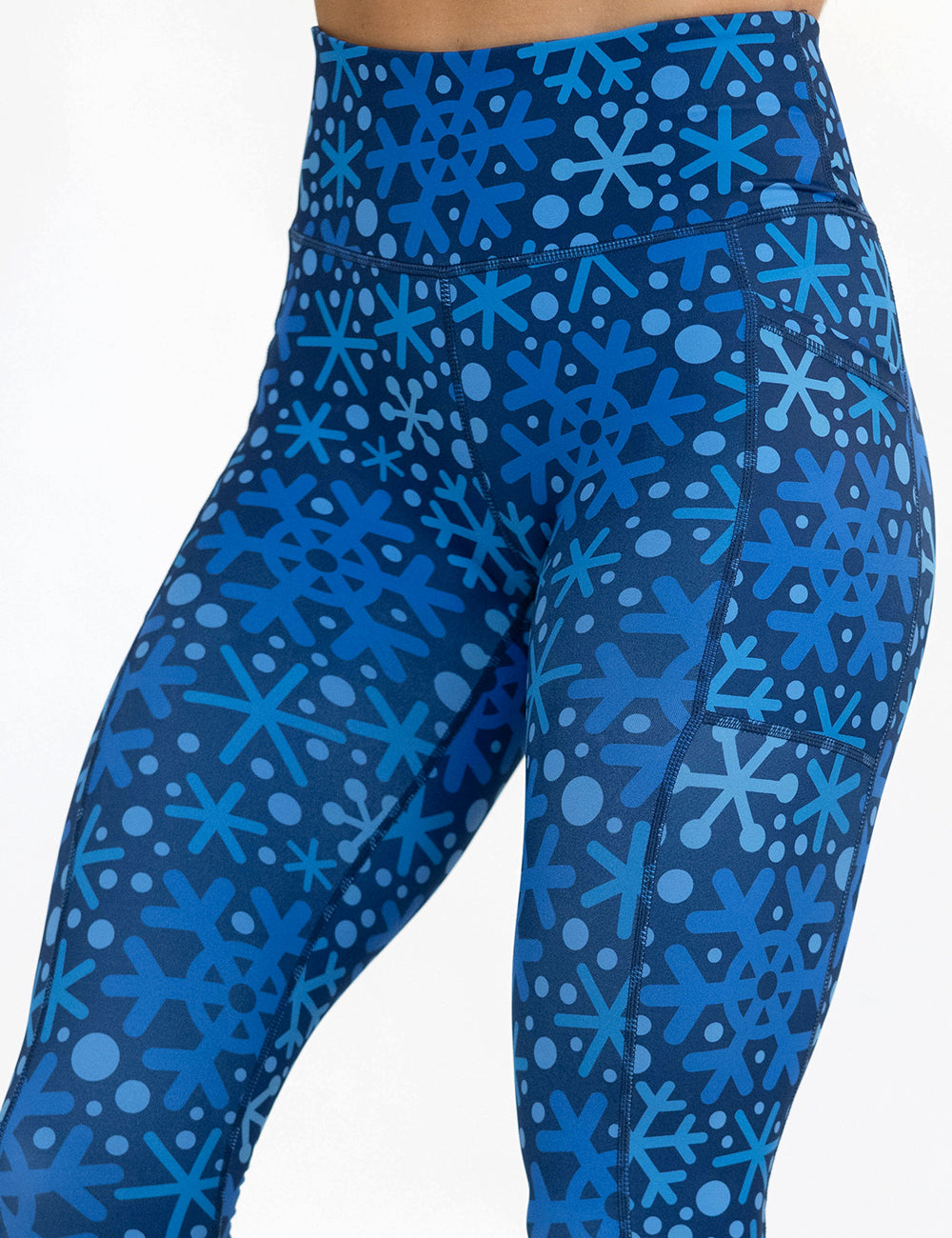 close up of the blue snowflakes on a dark blue background leggings against a white background