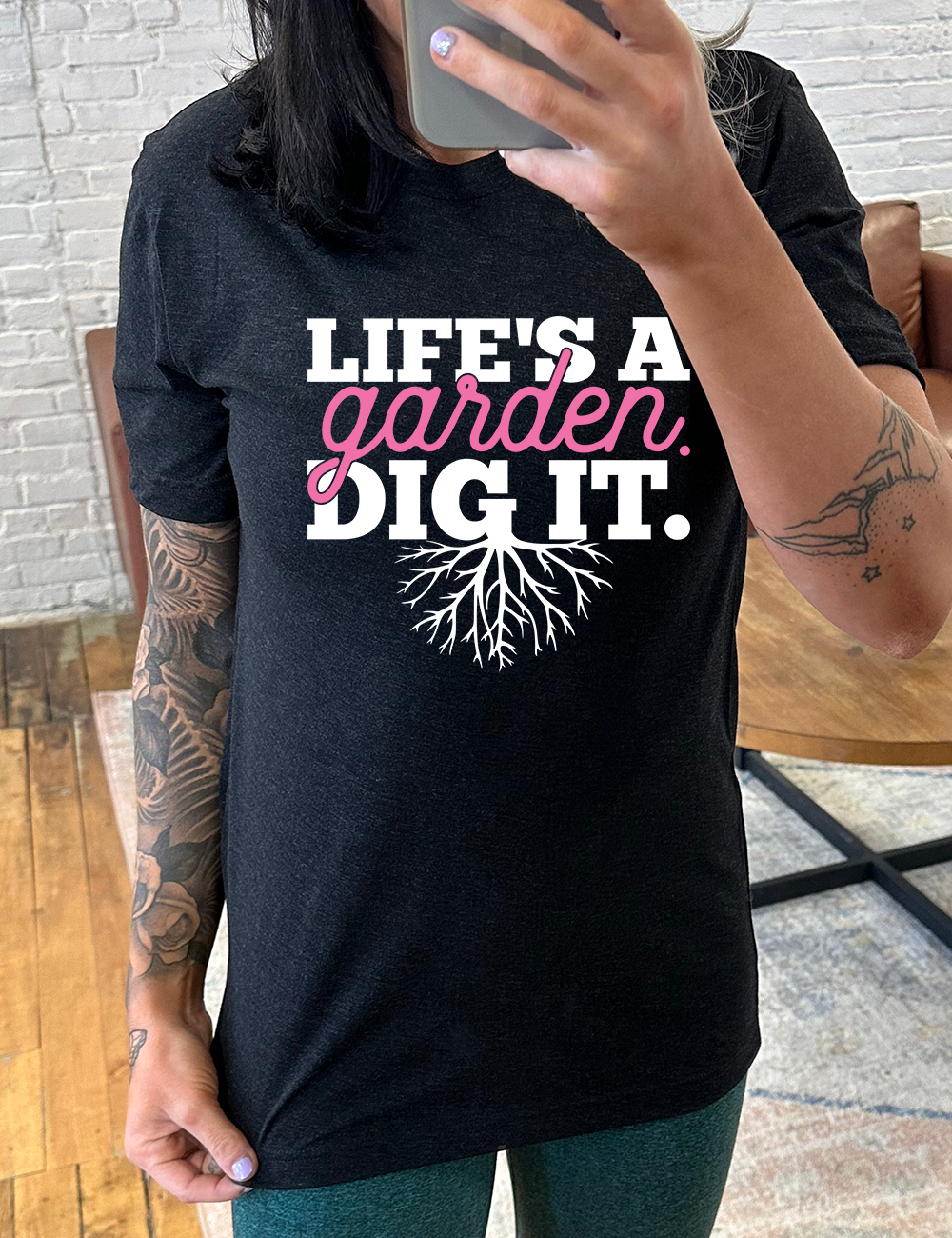 black unisex tee with the words "Life's a garden. Dig it." on it, with the "g" having roots growing down out the bottom of it