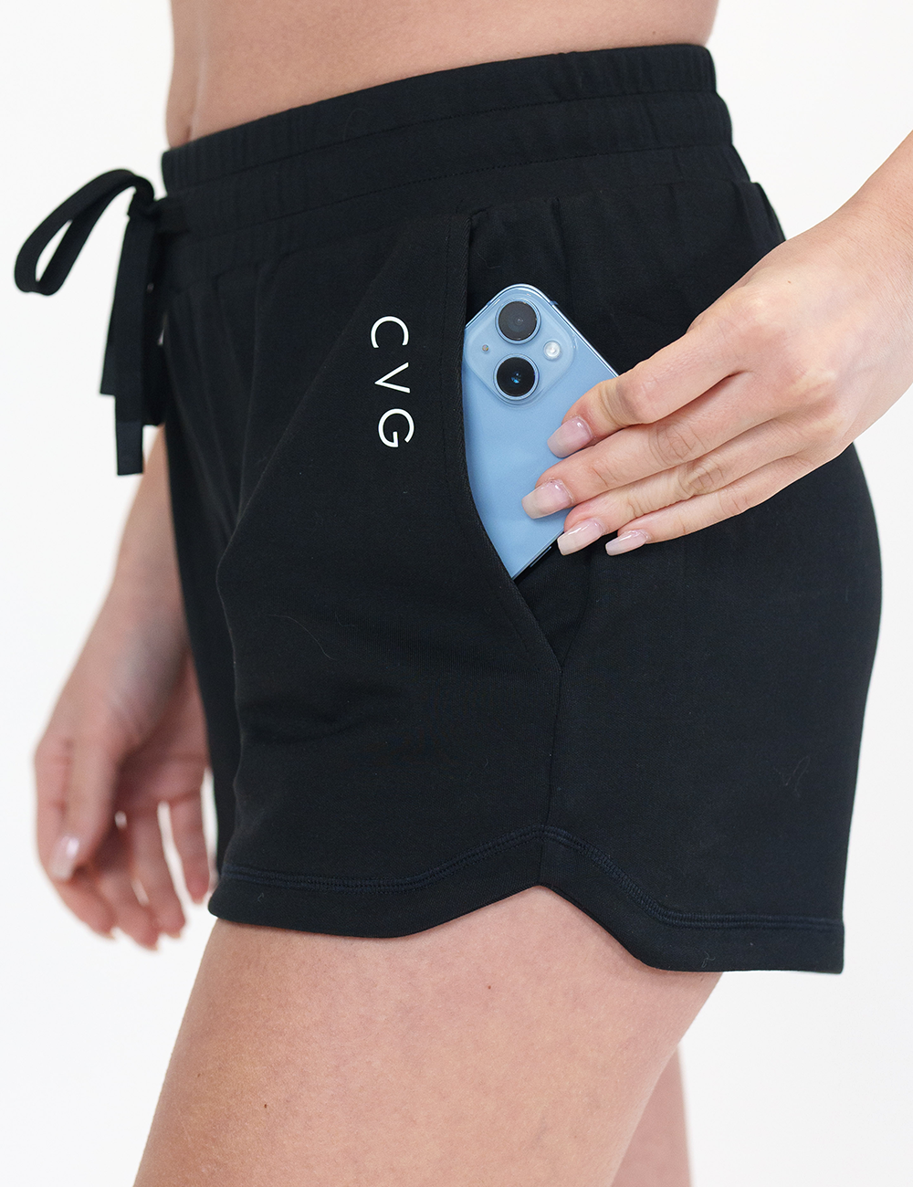 close up of the pocket on the black drawstring shorts holding a phone