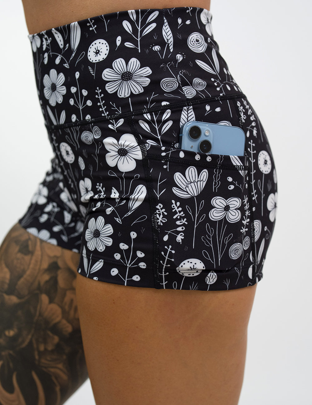 close up of the 2.5 inch black and white floral shorts with a phone in its pocket