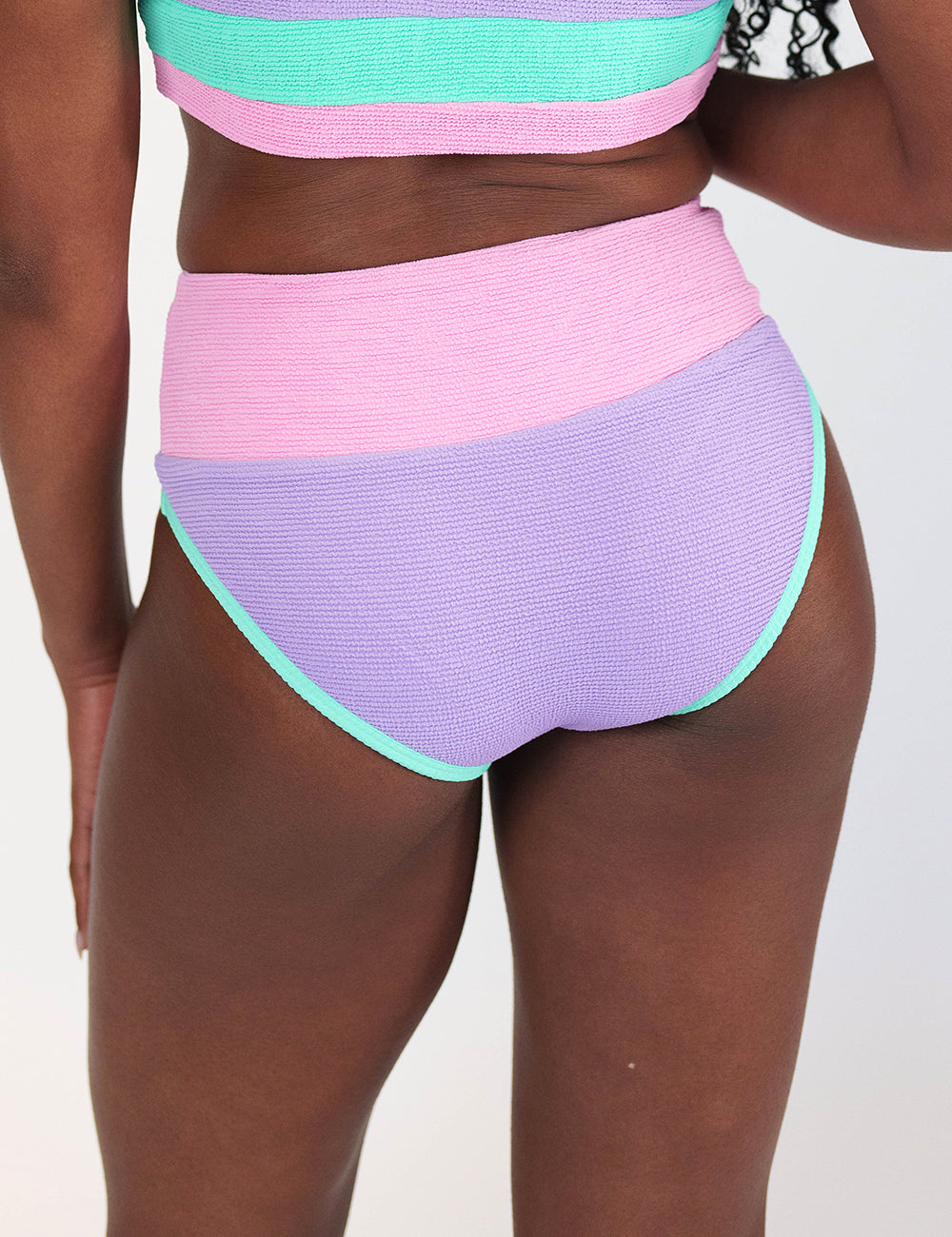 back of the pink, purple and teal bathing suit bottoms against a white background