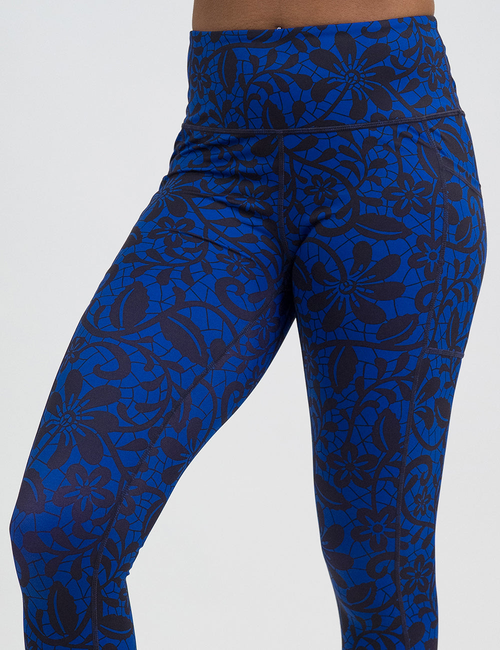 close up of black floral against a dark blue background pattern leggings against a white background