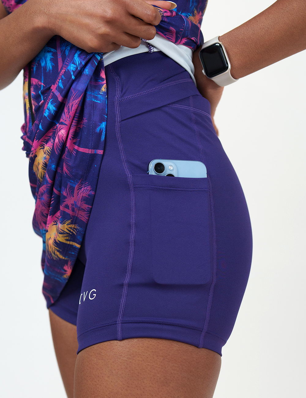 close up of the colorful palm tree pattern dress pulled up to show a phone in the pocket of the shorts underneath