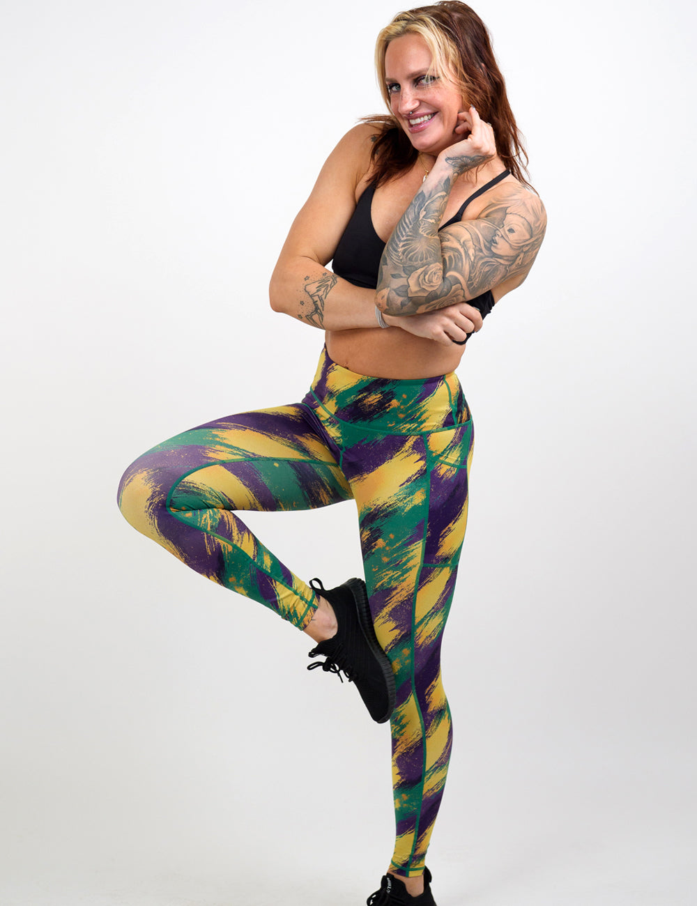Woman wearing colorful leggings and a black sports bra on a white background