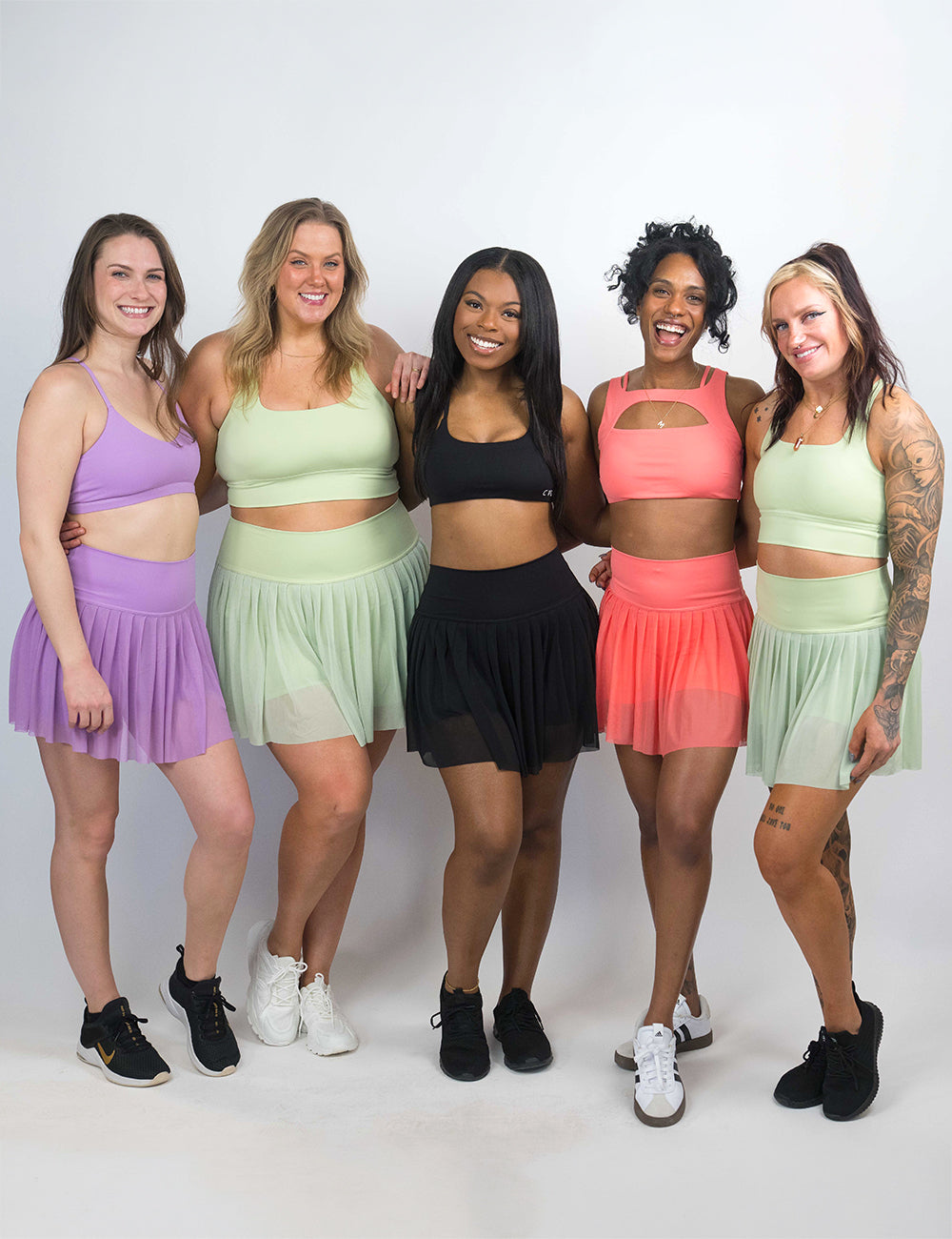 models wearing the pistachio, coral, black, and deep lilac motion skirts and matching bras