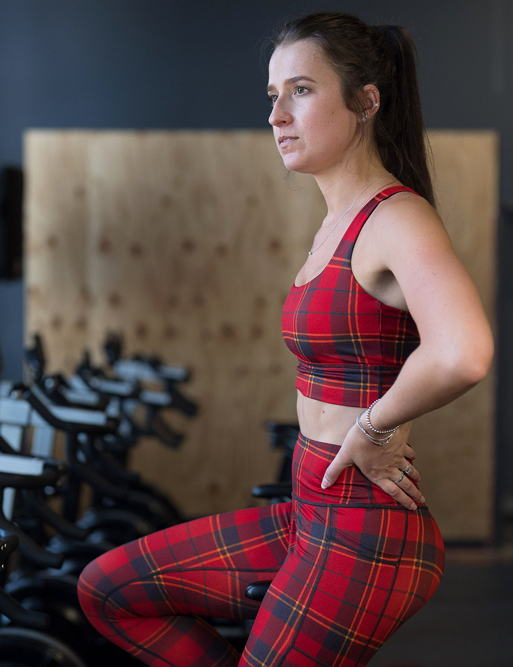 model wearing the red, dark red, and yellow plaid bra in the gym