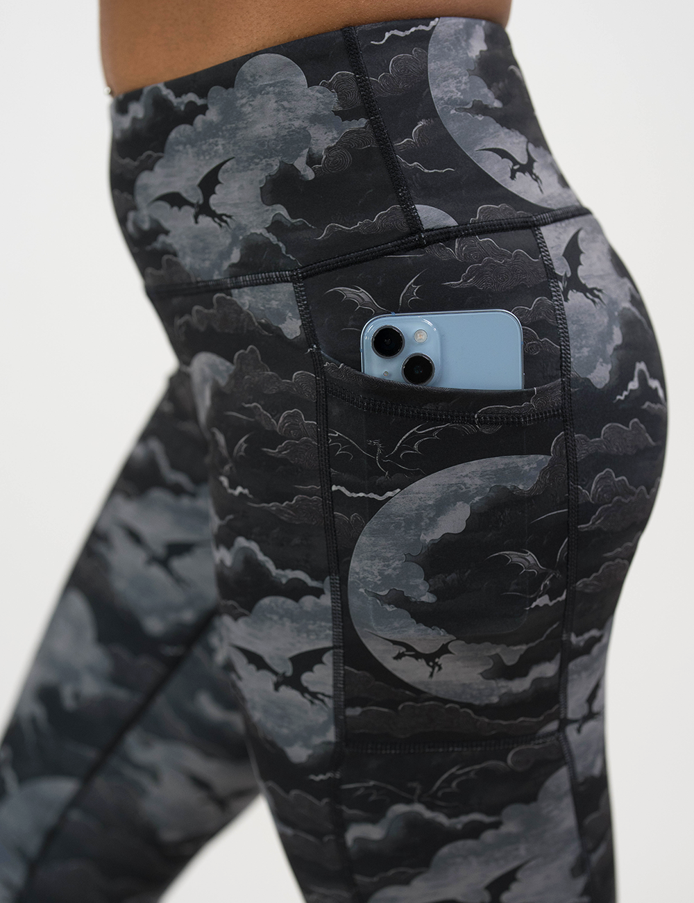 close up of the dark dragons against a moonlight night sky to show case the pocket which is holding a phone