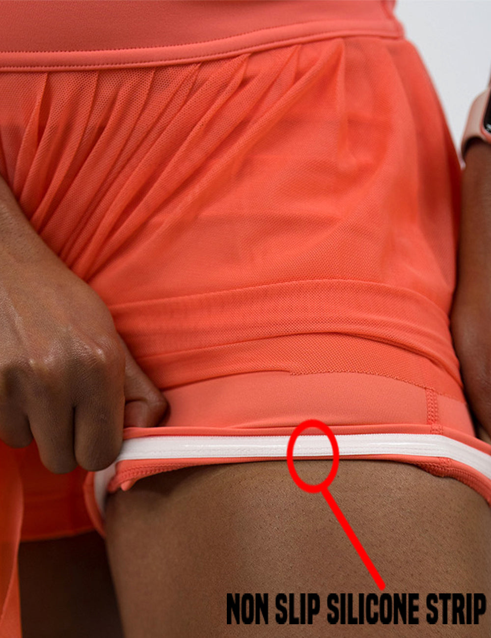close up of the coral sheer skirt pulled up to show the non slip silicone lining of the shorts underneath