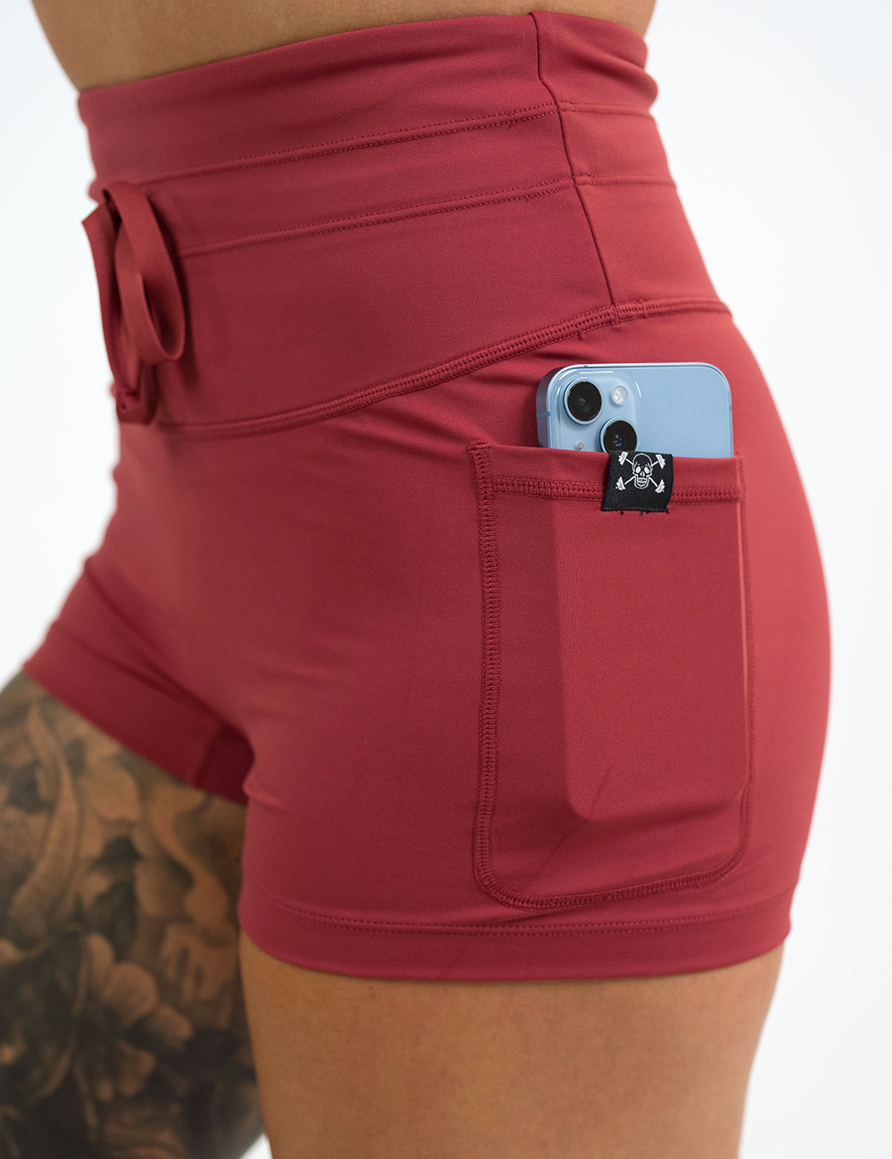 close up of the omni solid red 2.5 inch shorts with a phone in the pocket