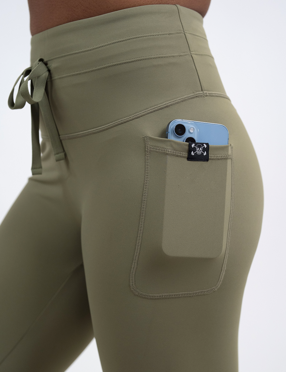close up of the omni green drawstring leggings pocket holding a phone